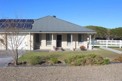 una casa blanca con paneles solares. en Worrigee Retreat Guesthouse, en Worragee