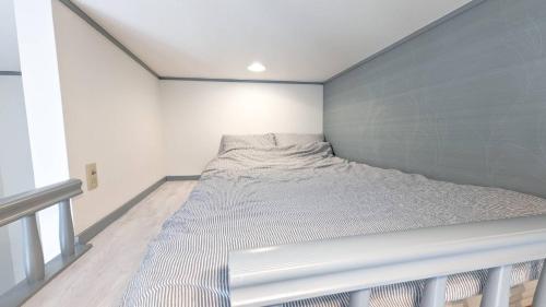 a bed in a room with a gray wall at 101 Hideaway, Apartment with loft in Tokyo