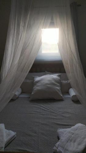 a bedroom with a bed with a window with curtains at KYTHIRA ISLAND RETREAT in Áyios Ilías