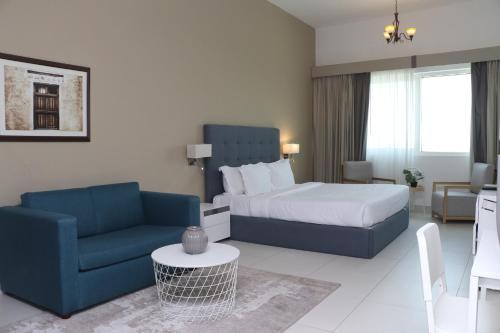 a bedroom with a bed and a couch and a chair at ABIDOS HOLIDAY HOMES Windsor Residence in Dubai