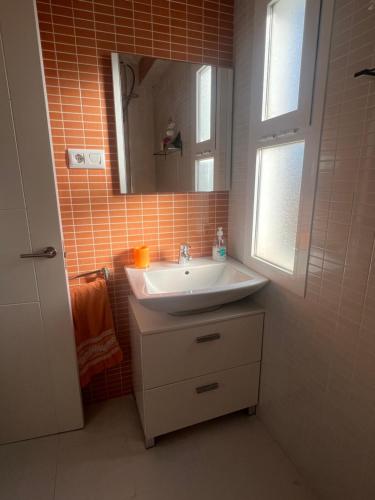 y baño con lavabo y espejo. en Apartamento junto a playa y cerca de campo de golf, en El Perellonet