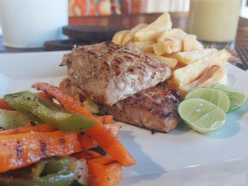 a plate of food with meat and fries and vegetables at Jaribu Beach Hotel in Paje