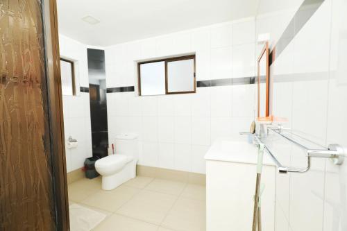 a white bathroom with a toilet and two windows at Gardenia Apartment-02 in Nadi