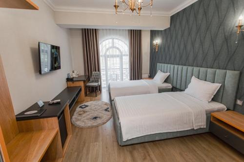 Habitación de hotel con 2 camas y escritorio en WELLFORT HOTEL, en Samarkand