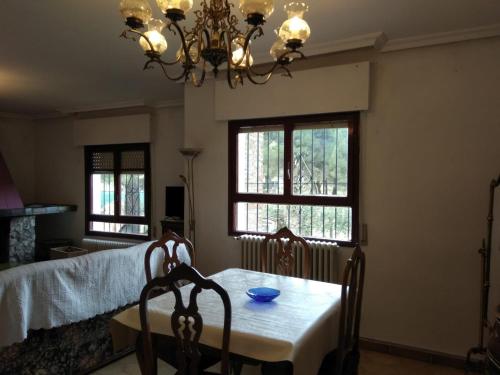 una sala da pranzo con tavolo, sedie e lampadario pendente di Taragudo a Laguna de Duero
