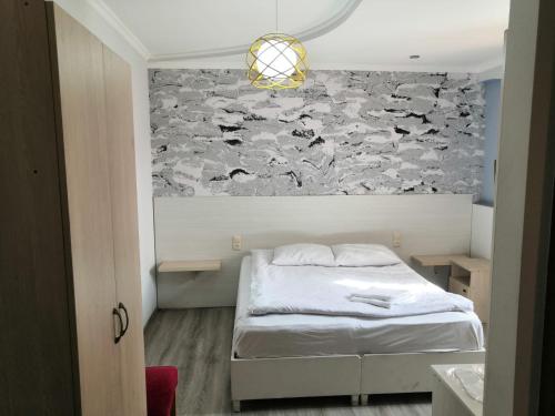 a bedroom with a bed and a stone wall at Hotel My Rose in Batumi