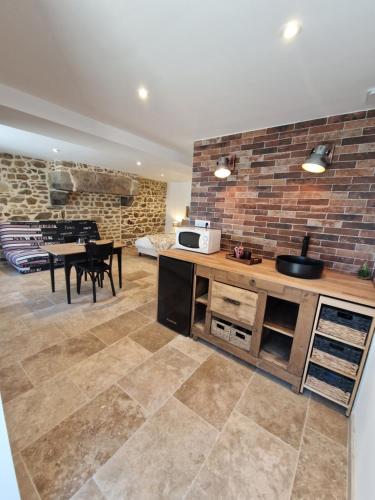 une cuisine avec une table et un mur en briques dans l'établissement Au fer à cheval, à Gandelain