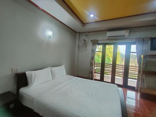 a bedroom with a white bed and a balcony at Chatchawan Resort in Ban Tha Sao