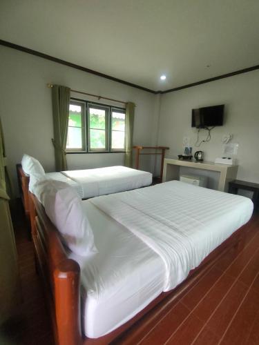 a bedroom with two twin beds and a television at Chatchawan Resort in Ban Tha Sao