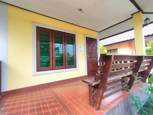 a wooden bench sitting on the front porch of a house at Chatchawan Resort in Ban Tha Sao