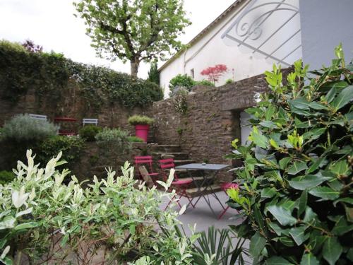 La Villa Garenne في فان: حديقة بها طاولة وكراسي وجدار من الطوب