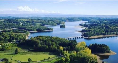 una vista aerea di un fiume alberato e di un ponte di Ma Cabane Au Bord Du Lac a Neuvic