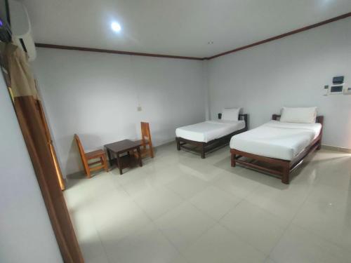 a room with two beds and a table and chairs at Chatchawan Resort in Ban Tha Sao