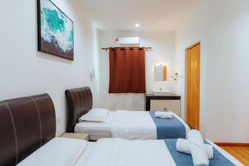 ein Hotelzimmer mit 2 Betten und einem Waschbecken in der Unterkunft MUSHROOMS INN in Semporna