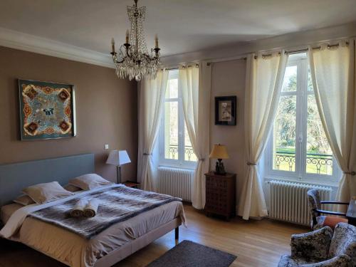 1 Schlafzimmer mit einem Bett, 2 Fenstern und einem Kronleuchter in der Unterkunft Chambres d'Hôtes Côté Parc-Côté Jardin avec parking privé gratuit in Nevers