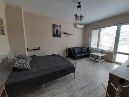 a bedroom with a black bed and a couch at Lefterov's Guests Suite in Varna City