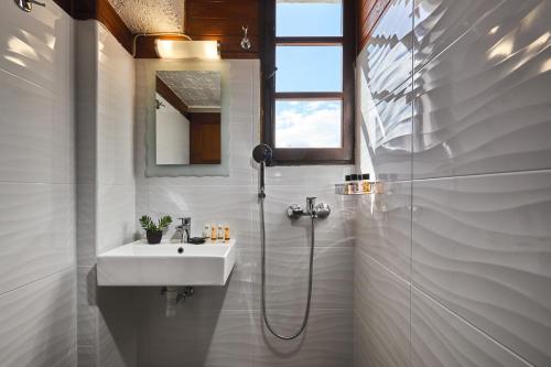 een witte badkamer met een wastafel en een douche bij Mila Malia Studios Hotel in Malia