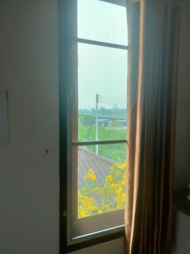 a window with a view of a field of yellow flowers at Chatchawan Resort in Ban Tha Sao