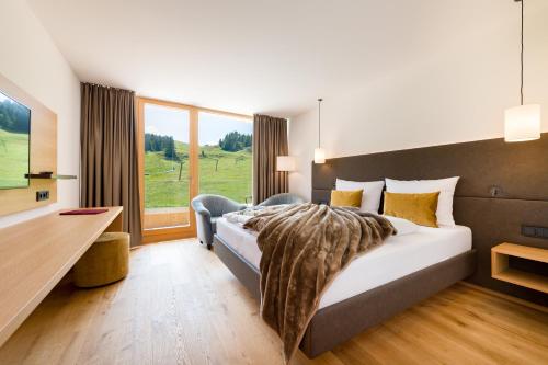 a hotel room with a bed and a large window at Almhotel Hochhäderich in Riefensberg