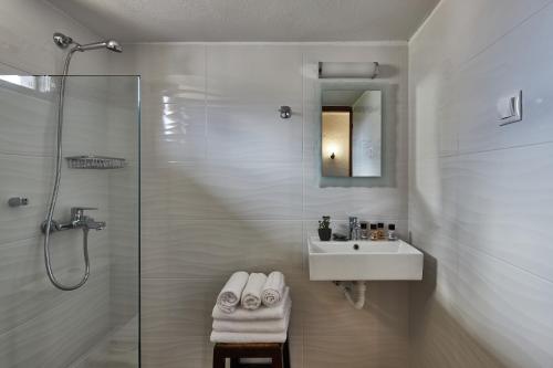 a white bathroom with a sink and a shower at Mila Malia Studios Hotel in Malia