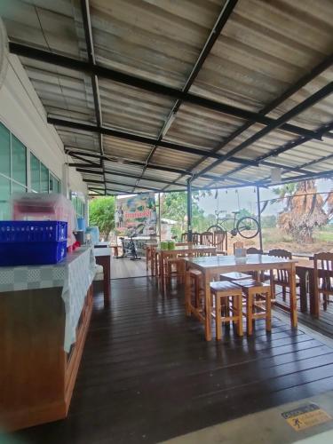 a restaurant with wooden tables and chairs and a counter at Chatchawan Resort in Ban Tha Sao
