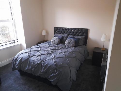 a bedroom with a large bed with blue pillows at Kirkcudbright Holiday Apartments - Apartment E in Kirkcudbright