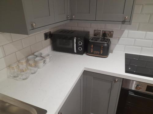 eine Küchentheke mit Mikrowelle und Tassen darauf in der Unterkunft Kirkcudbright Holiday Apartments - Apartment E in Kirkcudbright