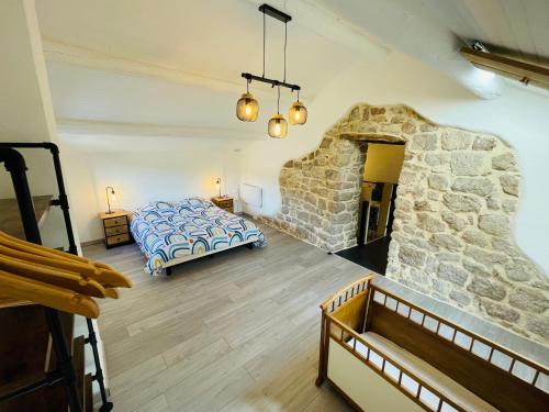 - une chambre avec un lit et un mur en pierre dans l'établissement Le Planzollais, à Planzolles
