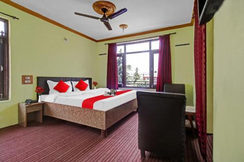 a bedroom with a bed with red pillows and a window at OYO Hotel Jay Palace in Srinagar