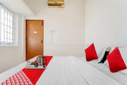 a white bed with red pillows and a blender on it at Flagship Cruze Residency in Coimbatore