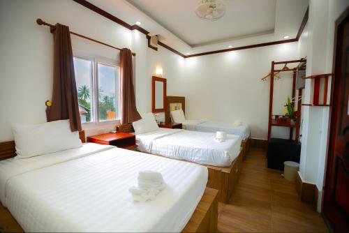 a hotel room with two beds and a window at Nana Vientiane Hotel in Vientiane