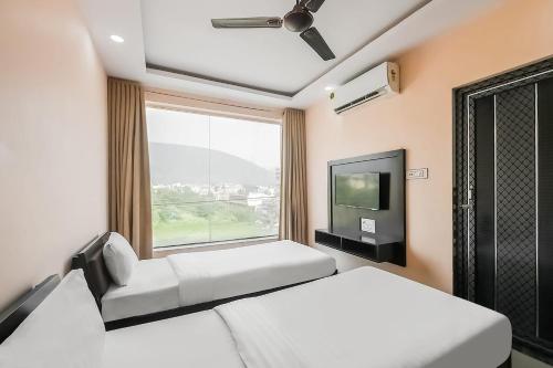 sypialnia z 2 łóżkami, telewizorem i oknem w obiekcie OYO The Orchid w mieście Jamshedpur