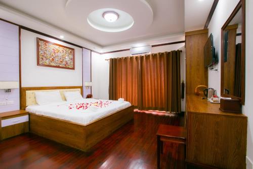Un dormitorio con una cama con flores rojas. en Nana Vientiane Hotel en Vientián