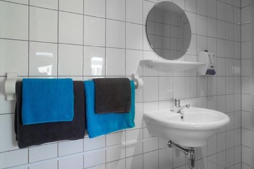 un bagno bianco con asciugamani blu e un lavandino di De Mariahoeve a Terherne