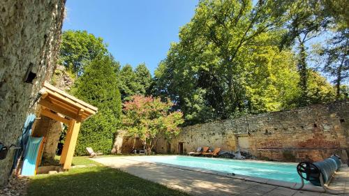 - une piscine dans une cour à côté d'un mur en pierre dans l'établissement Domaine de l'Esquibat, à Fumel