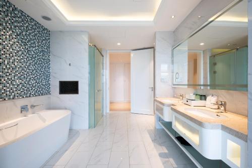 a bathroom with two sinks and a bath tub and a mirror at Wuhu Suning Universal Hotel in Wuhu