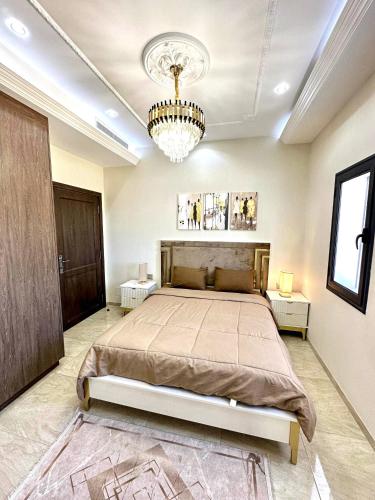 a bedroom with a large bed and a chandelier at Lovely 3 Bedrooms Fully Equipped With Central Ac in Rejiche