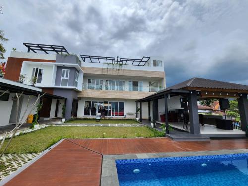 a house with a swimming pool in front of it at PURNAMA BALIGE HOTEL in Balige