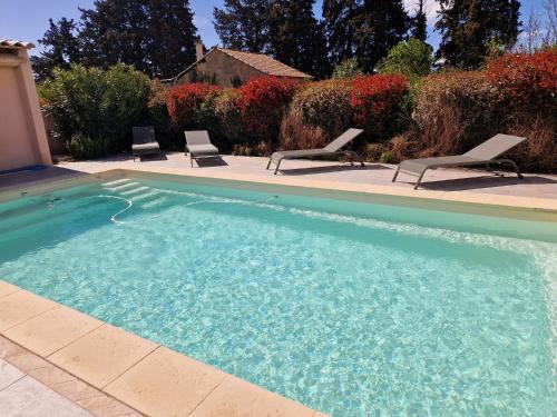 een zwembad met 2 ligstoelen ernaast bij La Villa Bleue in Saumane-de-Vaucluse