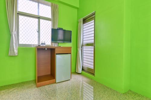 a green room with a television and a table and window at Chunfa B&B in Huxi