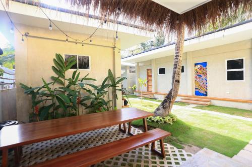 a wooden bench in a room with a palm tree at Beach People Hostel Bantayan Island in Ocoy