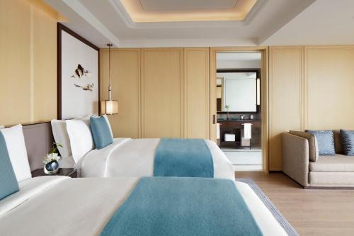 a hotel room with two beds and a chair at The St. Regis Qingdao in Qingdao