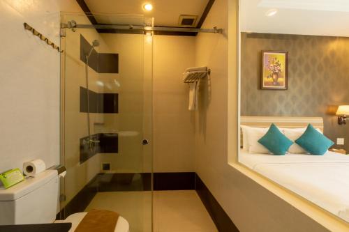 a bathroom with a shower and a bed and a toilet at Airport Saigon Hotel - Gần ẩm thực đêm chợ Phạm Văn Hai in Ho Chi Minh City