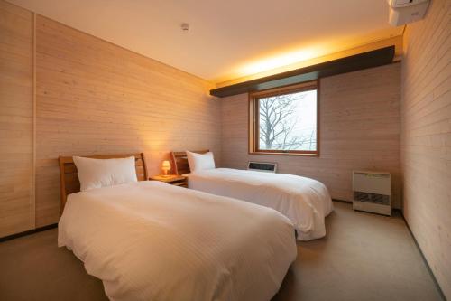 a bedroom with two beds and a window at Lake Toya Villa SUSUKIAN in Sobetsu