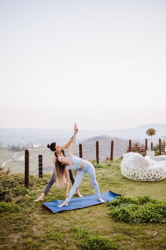 two people doing yoga on a hill with the ocean in the background at Boutique Hotel Municipio 1815 in Valdobbiadene