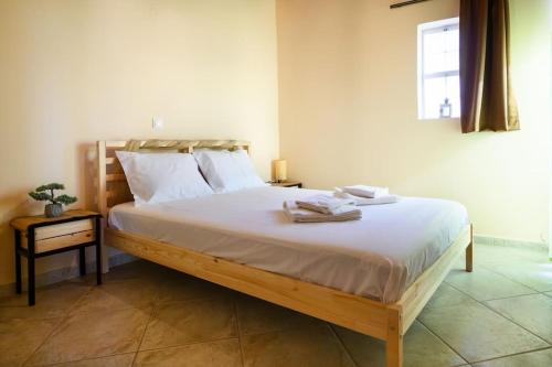 a bedroom with a large bed with white sheets and a window at Σπίτι με Τζάκι & Θέα in Mesinón