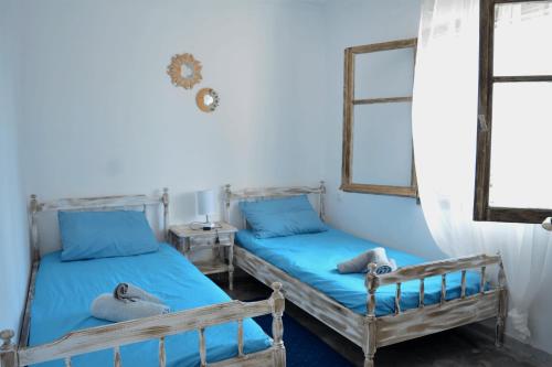 two beds in a room with blue walls and windows at Afroditi Ground floor apartment in Achílleion