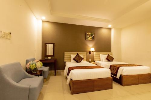 a hotel room with two beds and a chair at Airport Saigon Hotel - Gần ẩm thực đêm chợ Phạm Văn Hai in Ho Chi Minh City