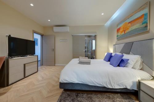 a bedroom with a large bed and a flat screen tv at Luxury Penthouse with Terrace and Views in St. Julianʼs