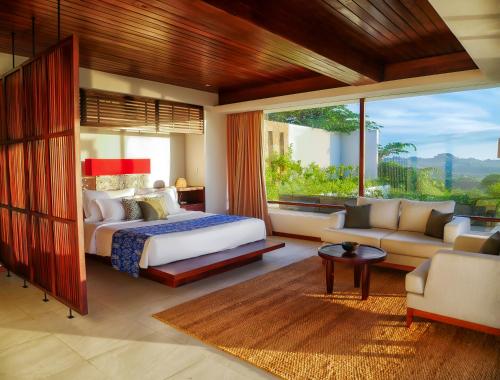 Un dormitorio con una cama y una sala de estar. en Jeeva Mandalika, en Kuta Lombok